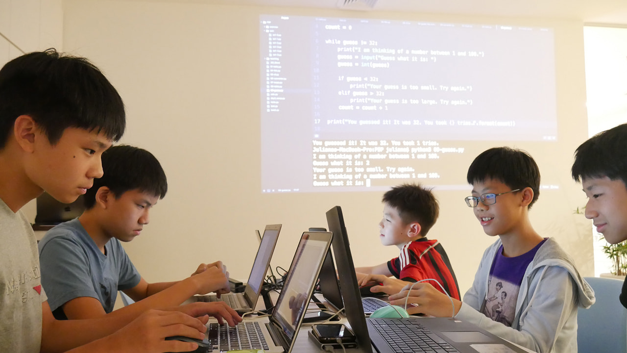 Teenagers writing Python on laptops at LCCL