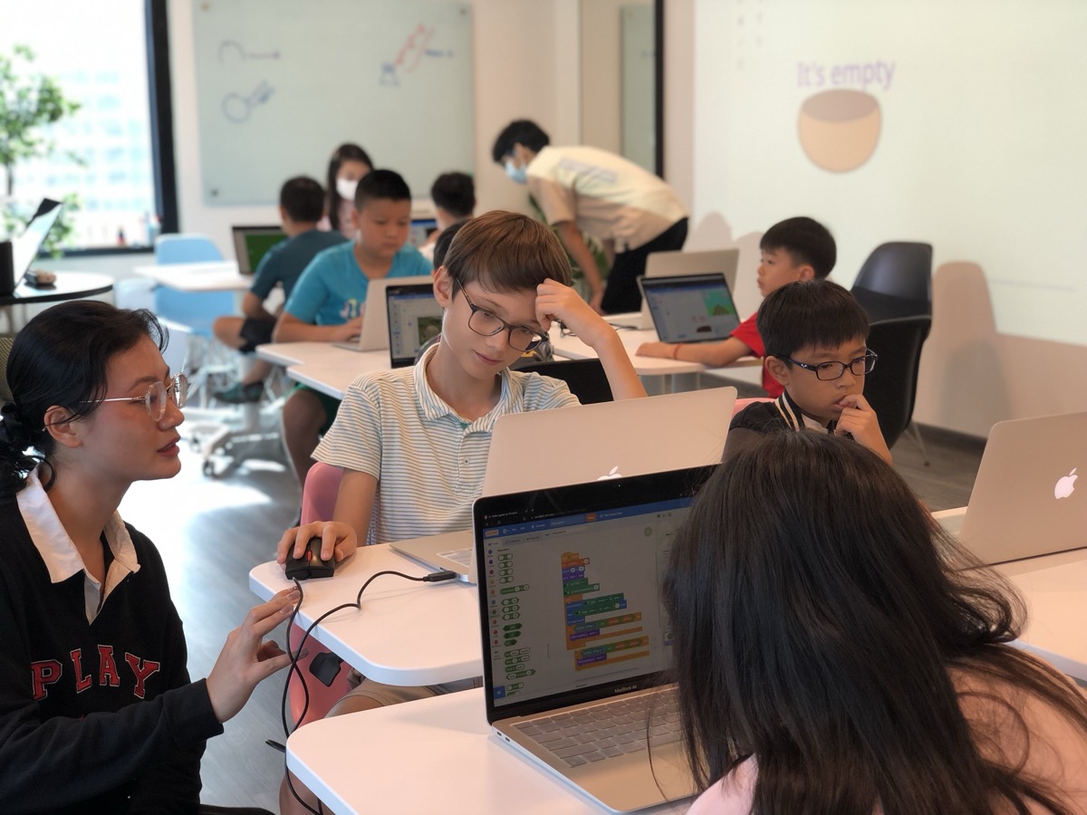 LCCL teacher mentoring students with Scratch on screen